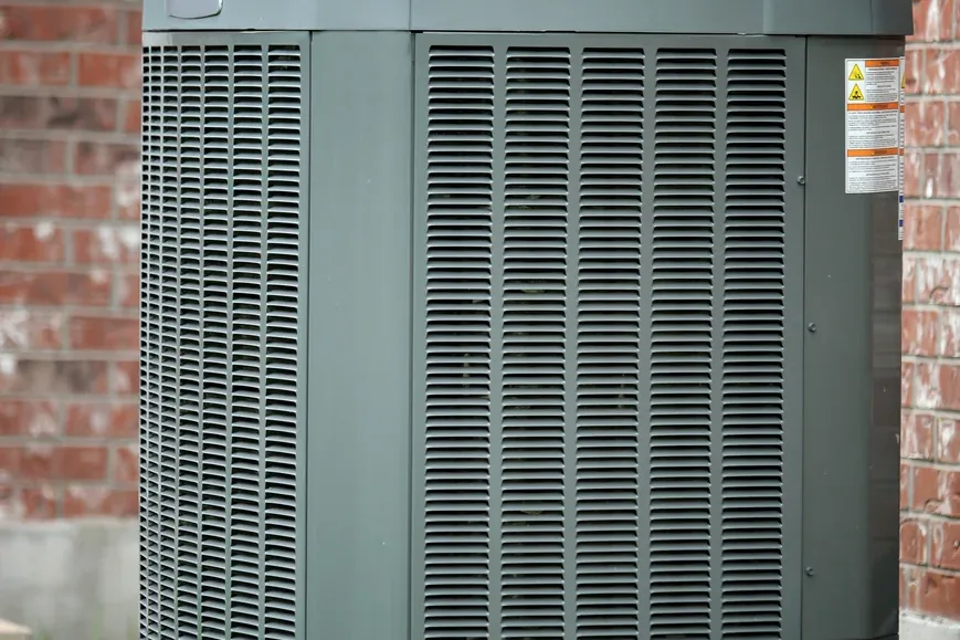 Residential air conditioner condenser beside a brick home