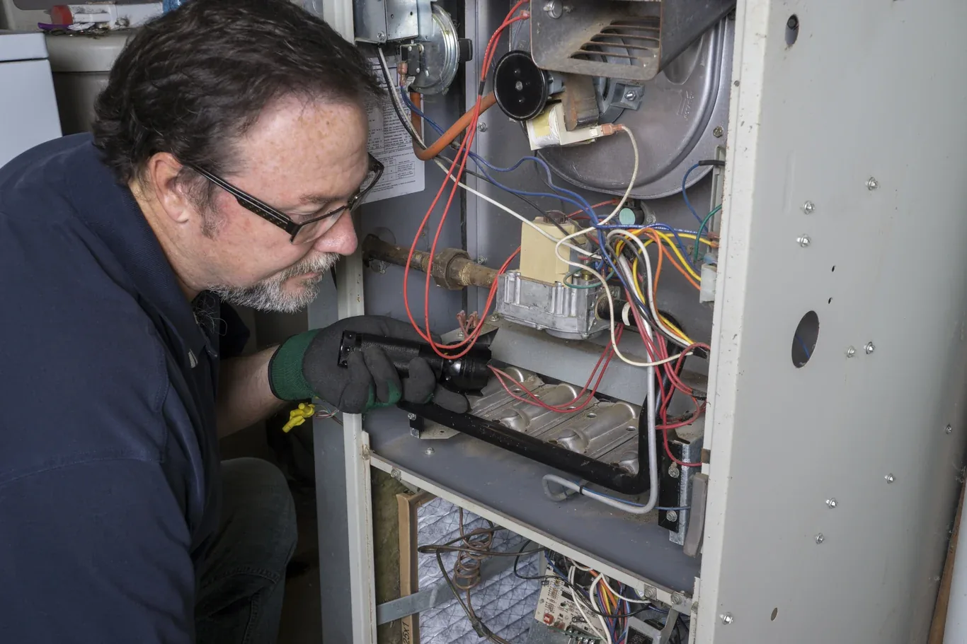 HVAC technician inspecting an open gas furnace