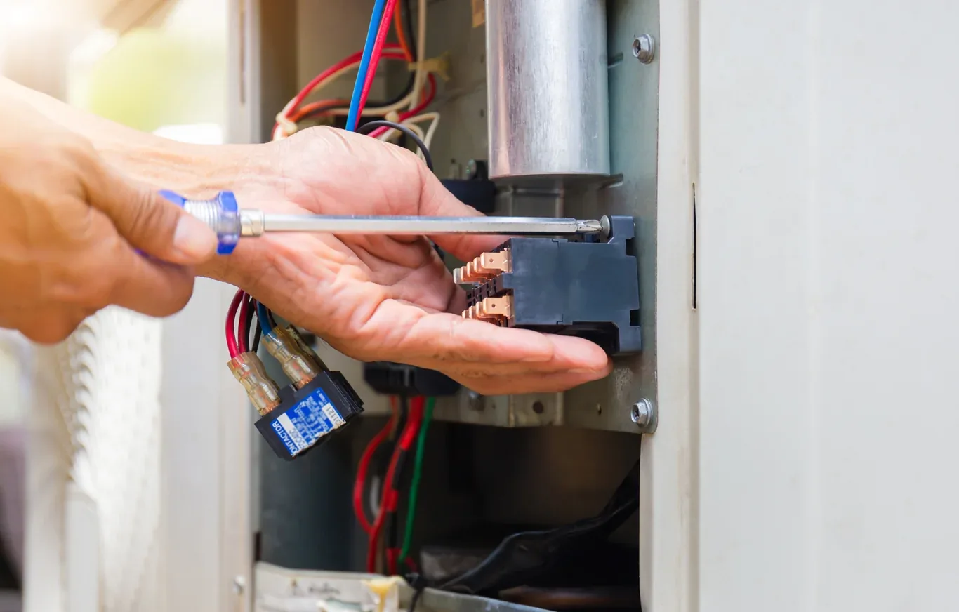 Technician repairing an air conditioner contactor and capacitor